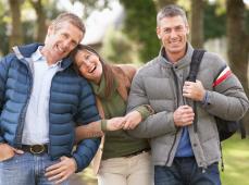Dos hombres y una mujer con plumas y mochila sonriendo