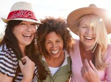 Tres chicas posando y sonriendo con sombreros de paja