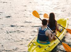 dos personas de espaldas manejando un kayak en el agua