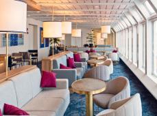 Sala donde hay sillones y mesas de color beis con lamparas encendidas