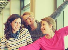 Tres chicas posando sonriendo y con los brazos en alto