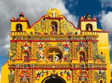 Fachada de una iglesia de color amarillo y con ornamentos en color rojo
