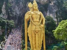 Templo hindú con una figura gigantesca en color oro y a su lado escalones que suben a la montaña