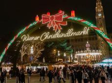 foto nocturna de la entrada del mercado navideño de Viena, con un arco de luces y un gran lazo rojo