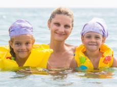 una mujer con dos niñas con flotadores en el mar