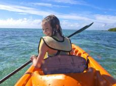 Niña montada en un kayax en el mar