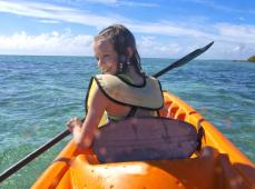 Niña montada en una canos remando en el mar