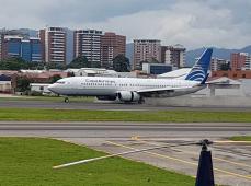 Avión parado en una pista de aterrizaje con bloques de viviendas al fondo