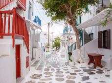 Callejuela estrecha en color blanco y las puertas en azul, el suelo con adoquines grises