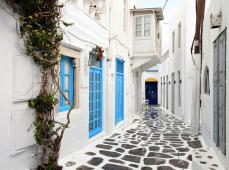 Callejuela estrecha en color blanco y las puertas en azul, el suelo con adoquines grises