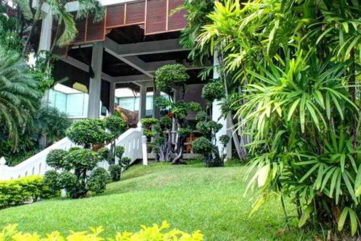 La entrada a un hotel con escalinatas rodeado de césped y setos
