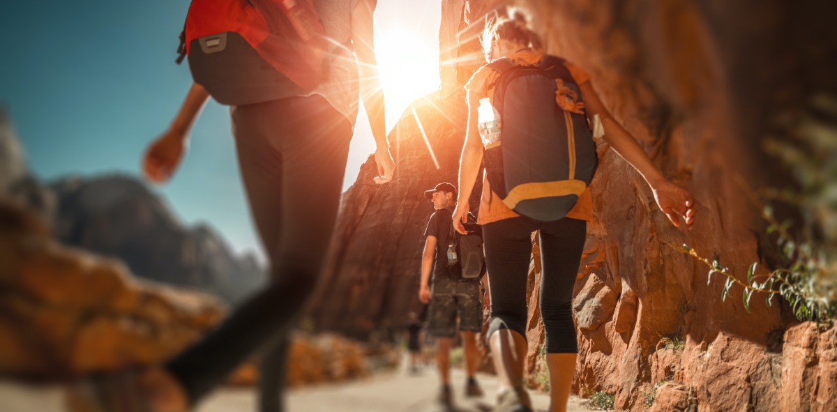 Senderistas de espaldas con sus mochilas caminando por una sendero de tierra
