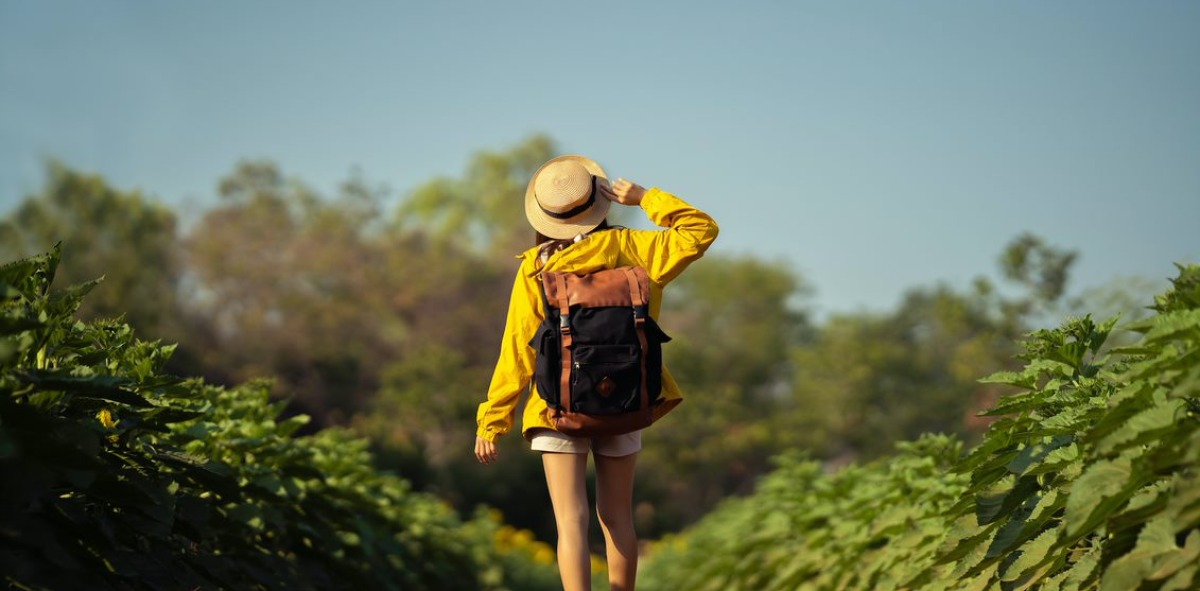 Chica de espaldas con mochila por un sendero de tierra