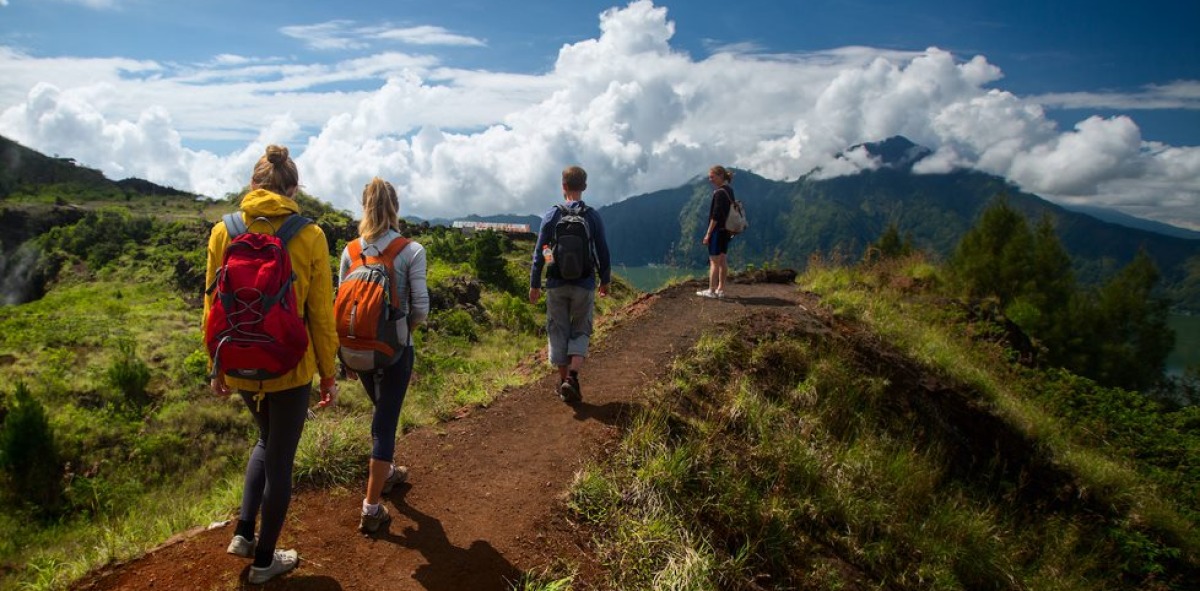 Chicas y chicos de espaldas por un camino de tierra por las montañas
