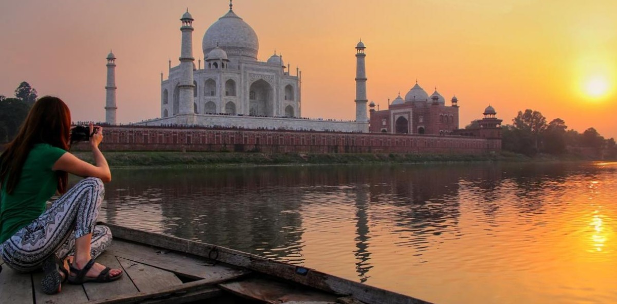 Mujer fotografiando el espectacular atardecer con el Templo del Taj Mahal