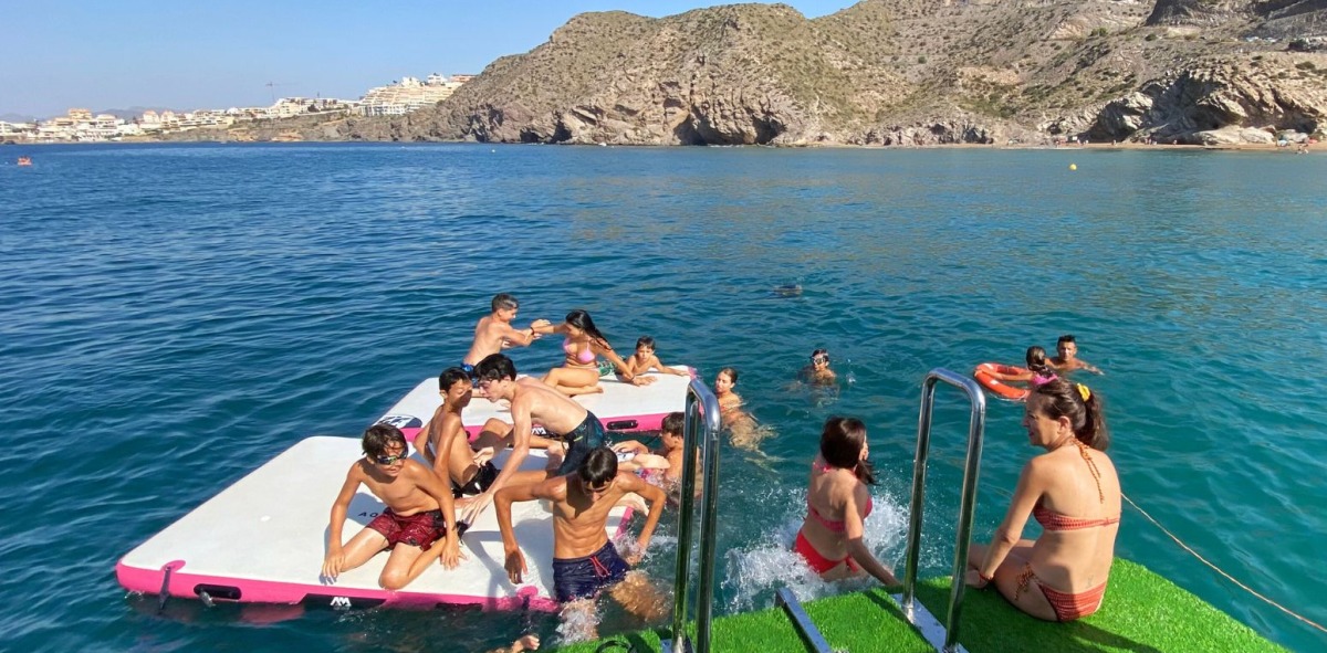Grupo de adolescentes montados en tablas grandes intentando no caerse