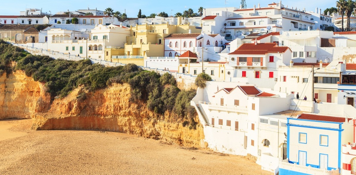 Casas en color blanco que dan a una playa de arena dorada