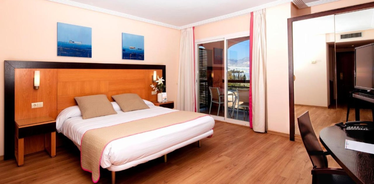 Habitación de un hotel donde aparece una cama grande y una terraza