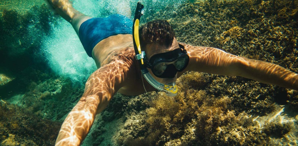 Joven haciendo snorkel debajo del mar