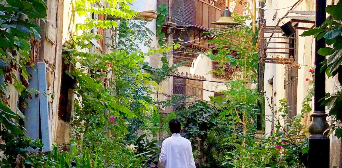 Hombre de blanco de espaldas paseando por una típica calle Saudita