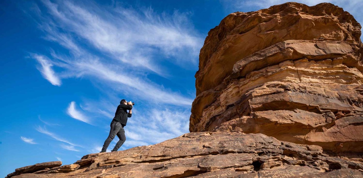 Hombre tomando foto a formaciones rocosas en el desierto