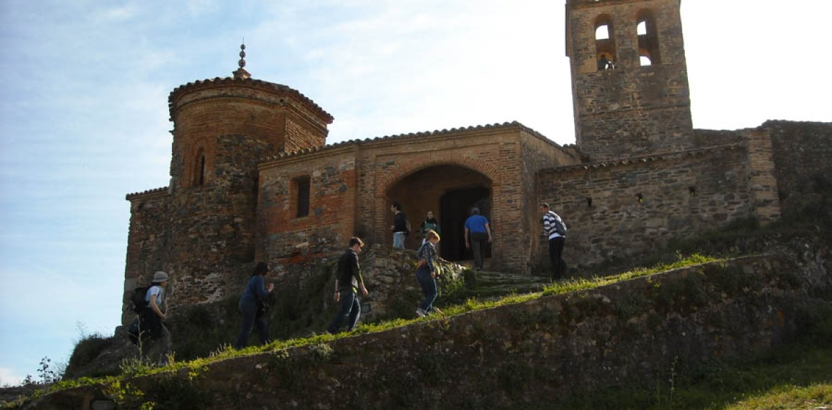 Grupo de gente subiendo a la entrada de un castillo en el pico de la montaña