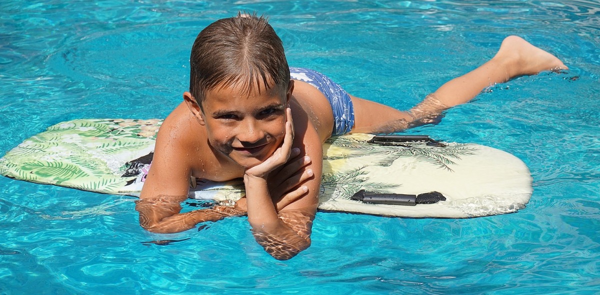 Niño encima de su tabla posando en el agua