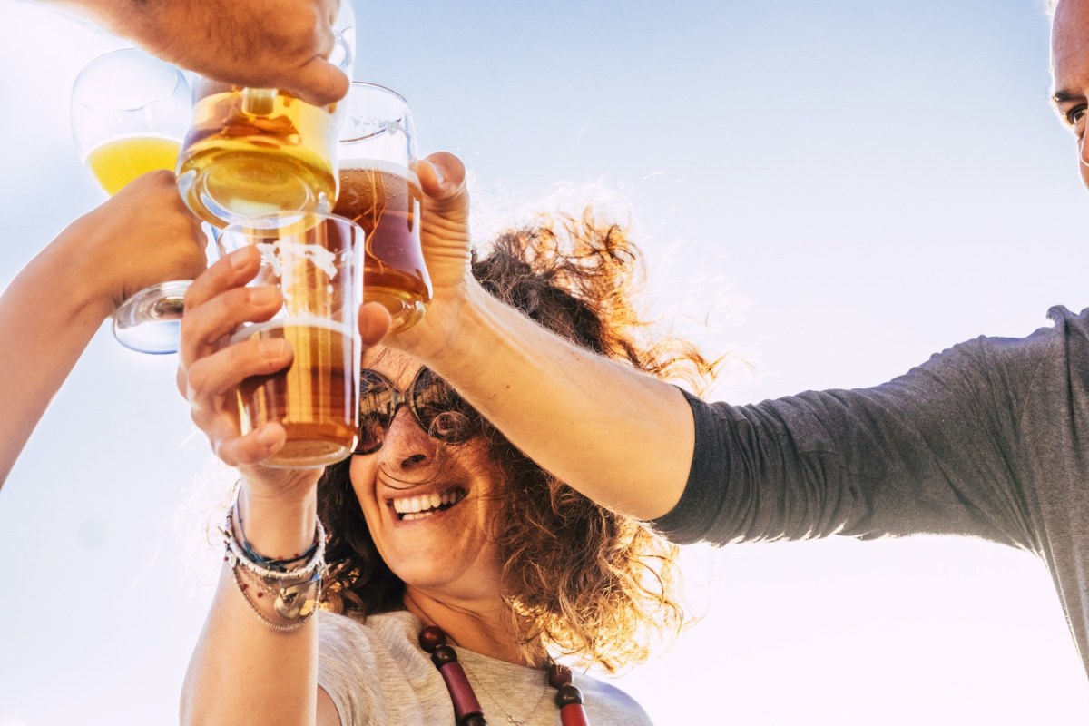 Haciendo un brindis, una mujer sonriendo chocando su bebida con otras