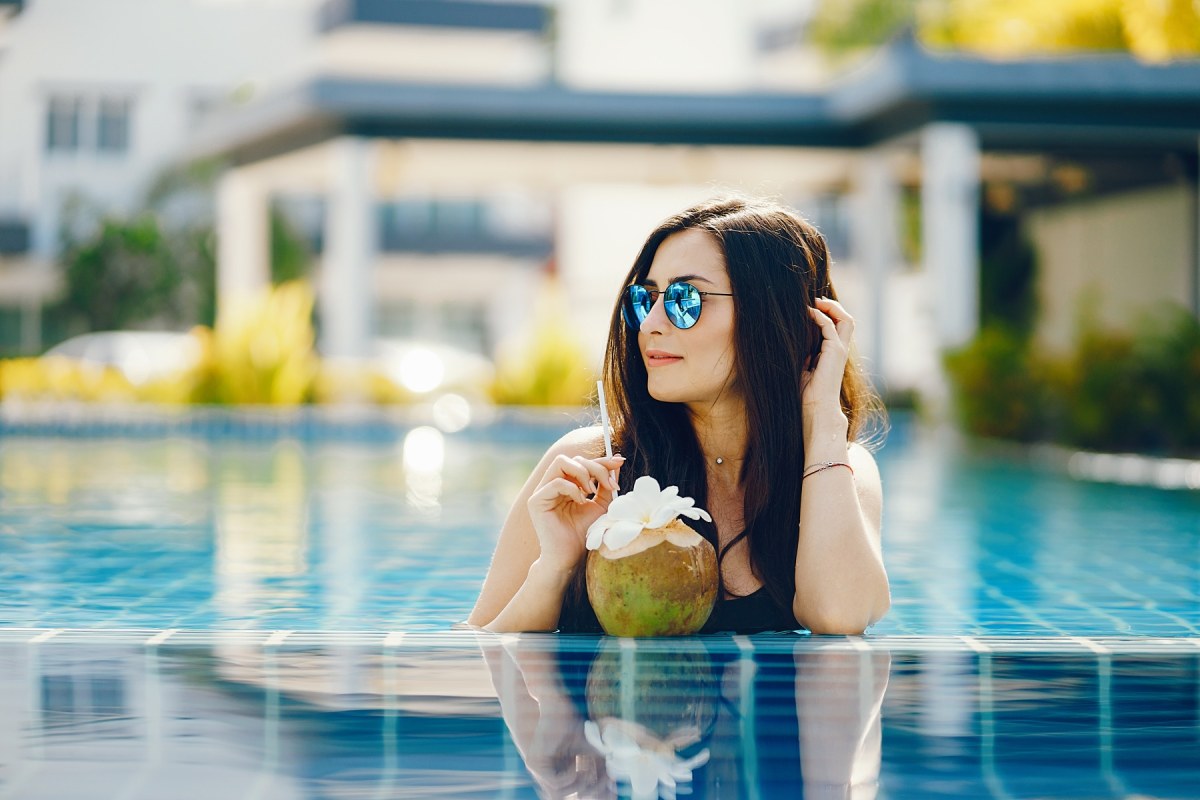 Chica single relajada en la piscina del hotel