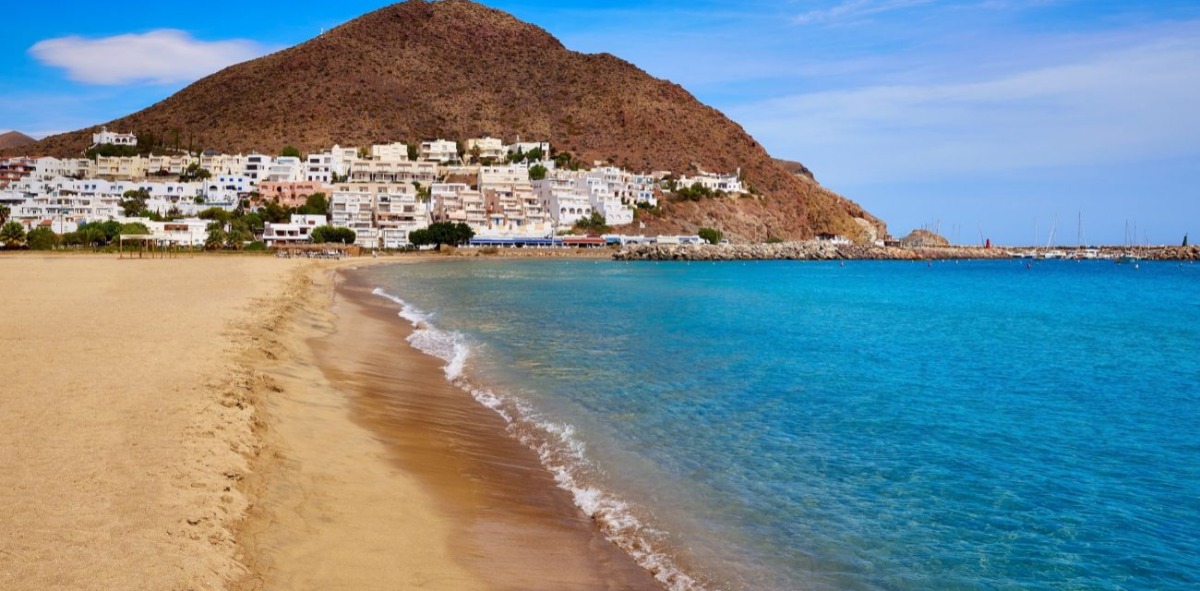 Pueblo con casas de color blanco en la ladera de una montaña y junto a la playa
