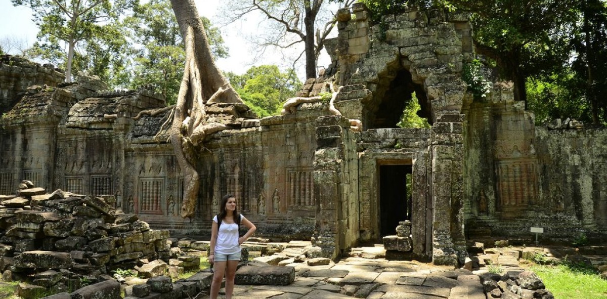 Turista admirando las ruinas de la antigua ciudad de Siem Reap tragadas por la selva