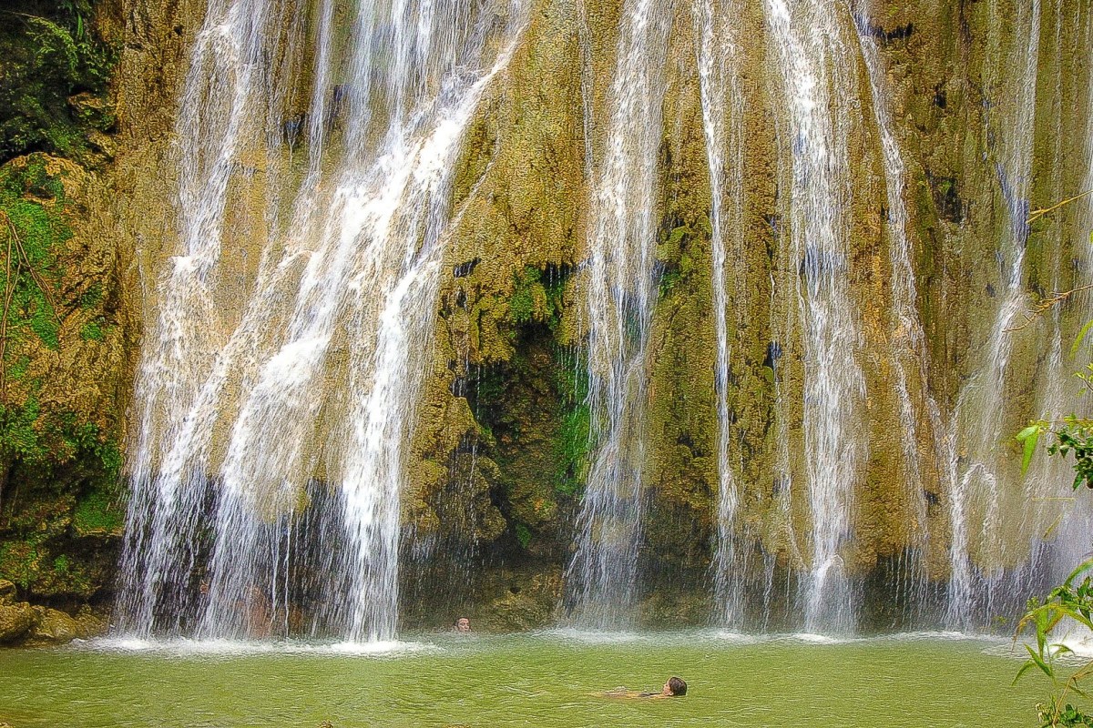 Salto de agua donde está una persona disfrutando del agua