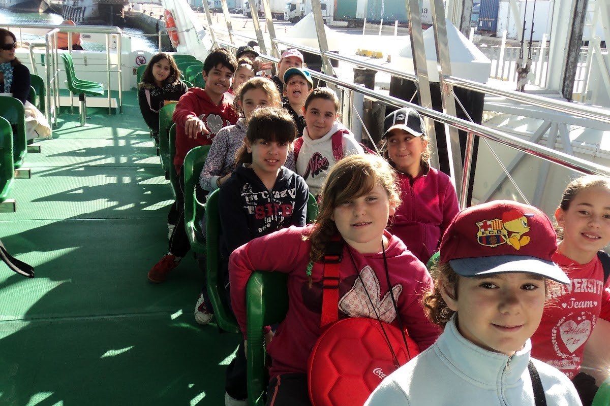 Grupo de niños sentados en el barco de recreo que les lleva a navegar
