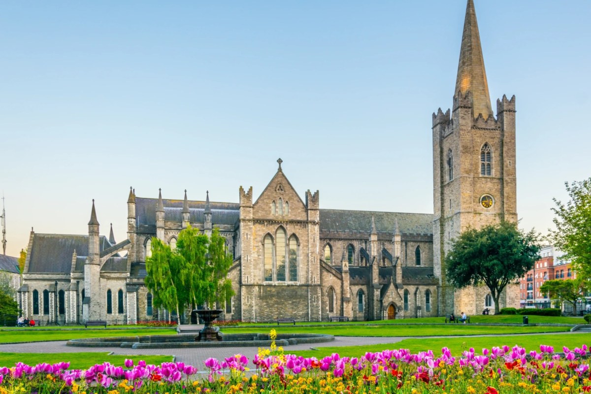Catedral de piedra con un jardín verde y flores