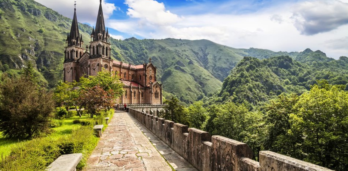 Camino de piedra al Santuario de Covadonga rodeado de montañas verdes