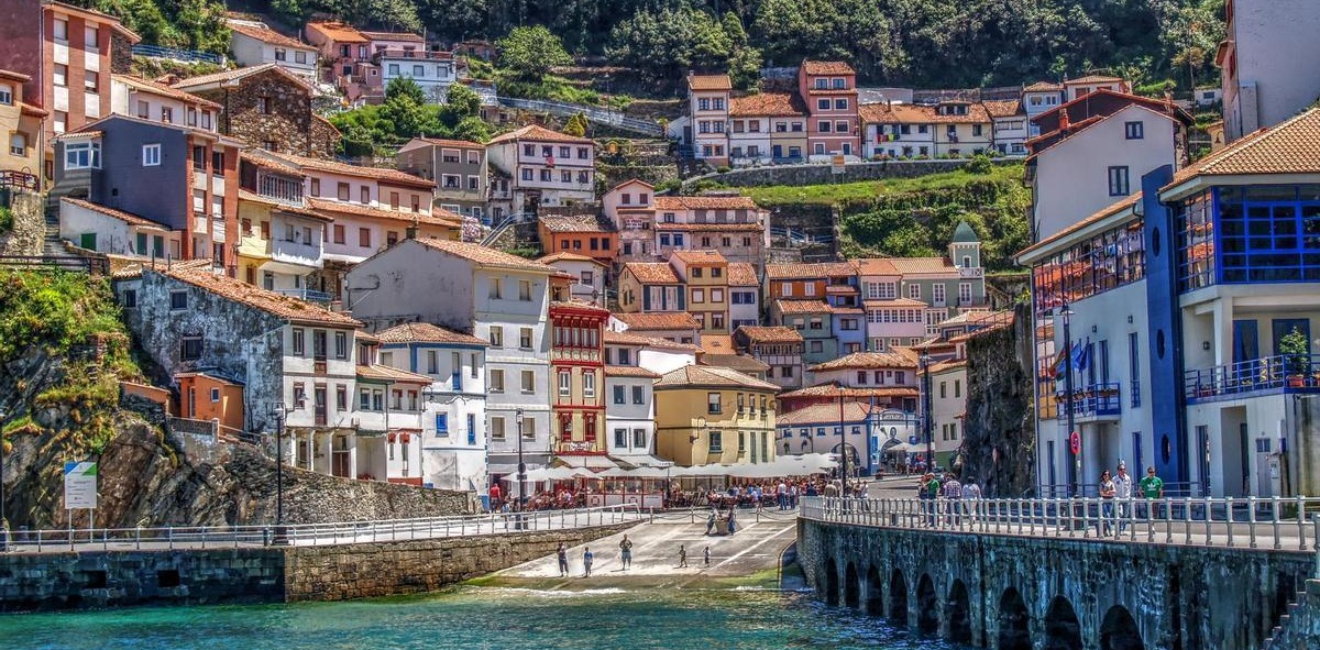 Pueblo en la ladera de una colina con casas escalonas que da a un puerto de mar