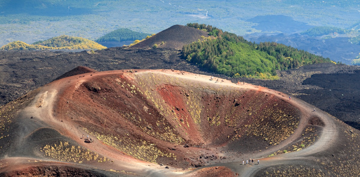 foto desde el cielo de la boca de un volcán y gente paseando por los caminos