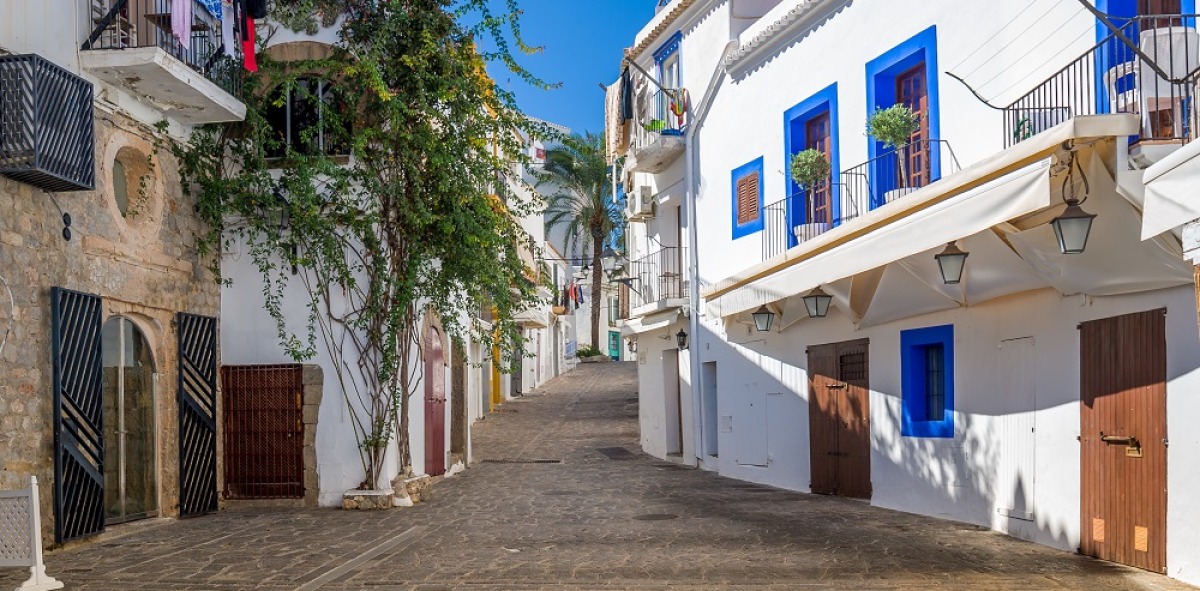 Calle adoquinada con sus casas blanqueadas y los marcos de las ventanas en color azul