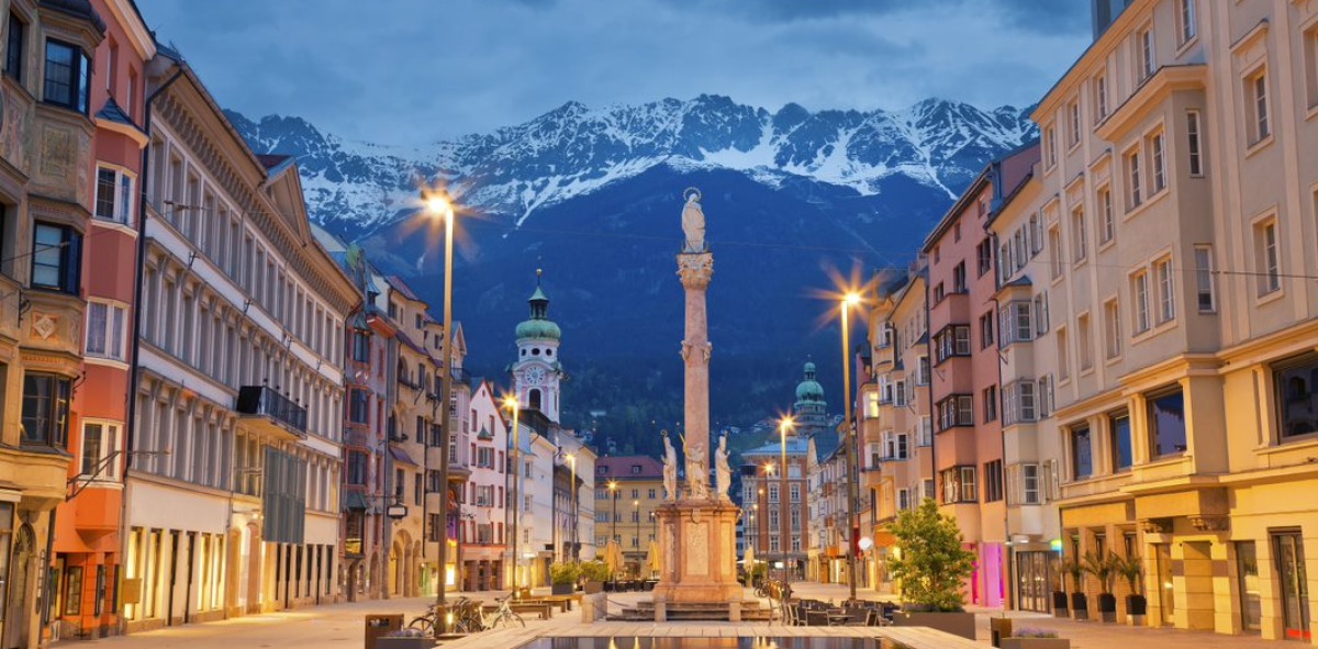 Calle ancha con una fuente en el medio y al fondo las grandes montañas nevadas
