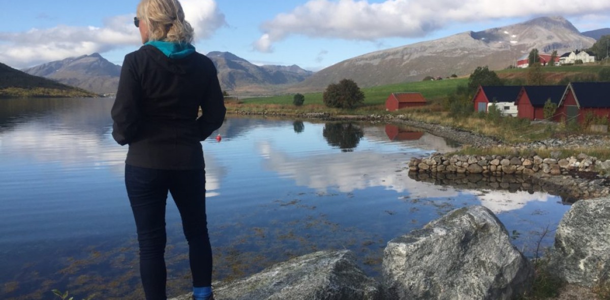 Mujer contemplando un lago junto a cabañas típicas de madera en las islas