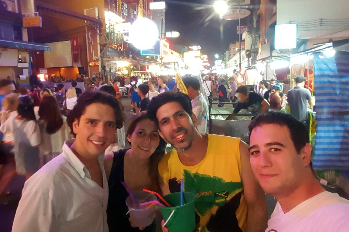Tres chicos y una chica posando en una calle muy concurrida por la noche