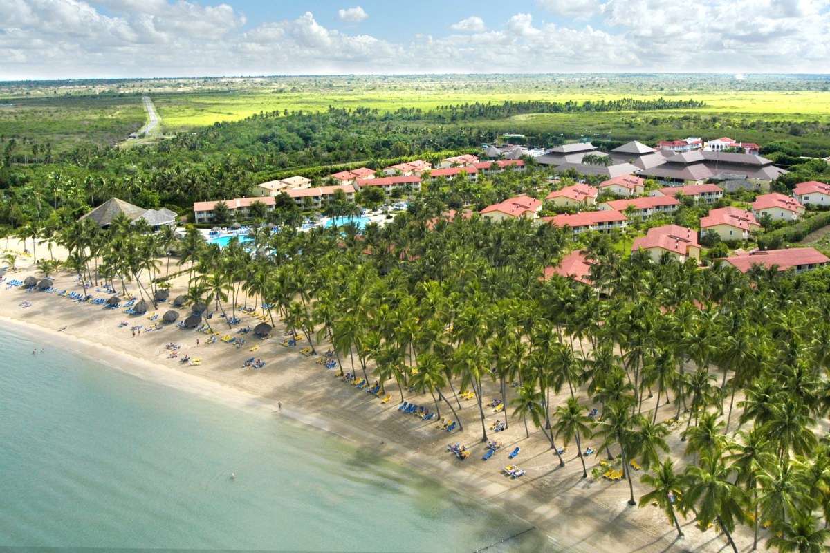 Panorámica desde el aire del complejo hotelero rodeado de vegetación al lado de la playa