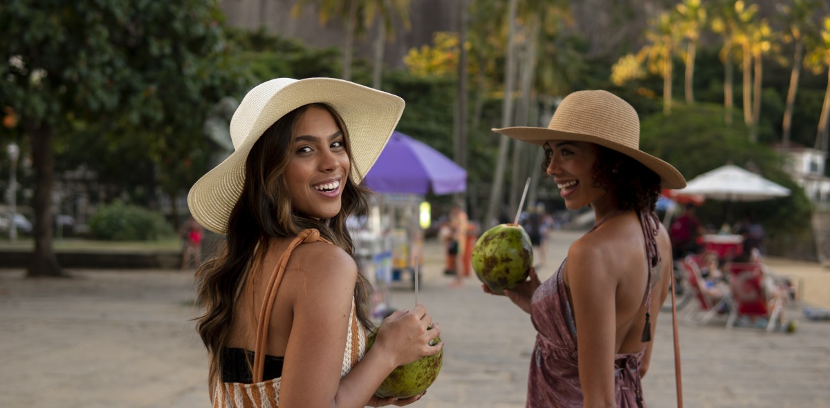 Amigas singles en la playa tomando agua de coco