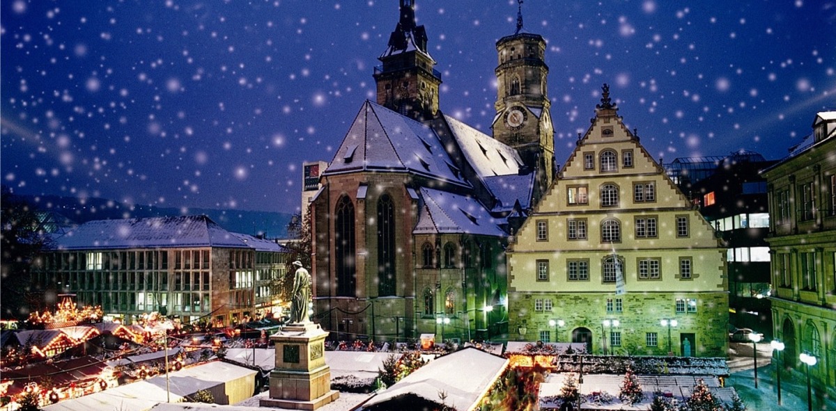 Plaza nevada con puestos navideños con la iglesia al fondo