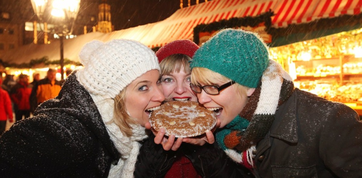 Tres chicas probando la gastronomía popular en el mercado navideño