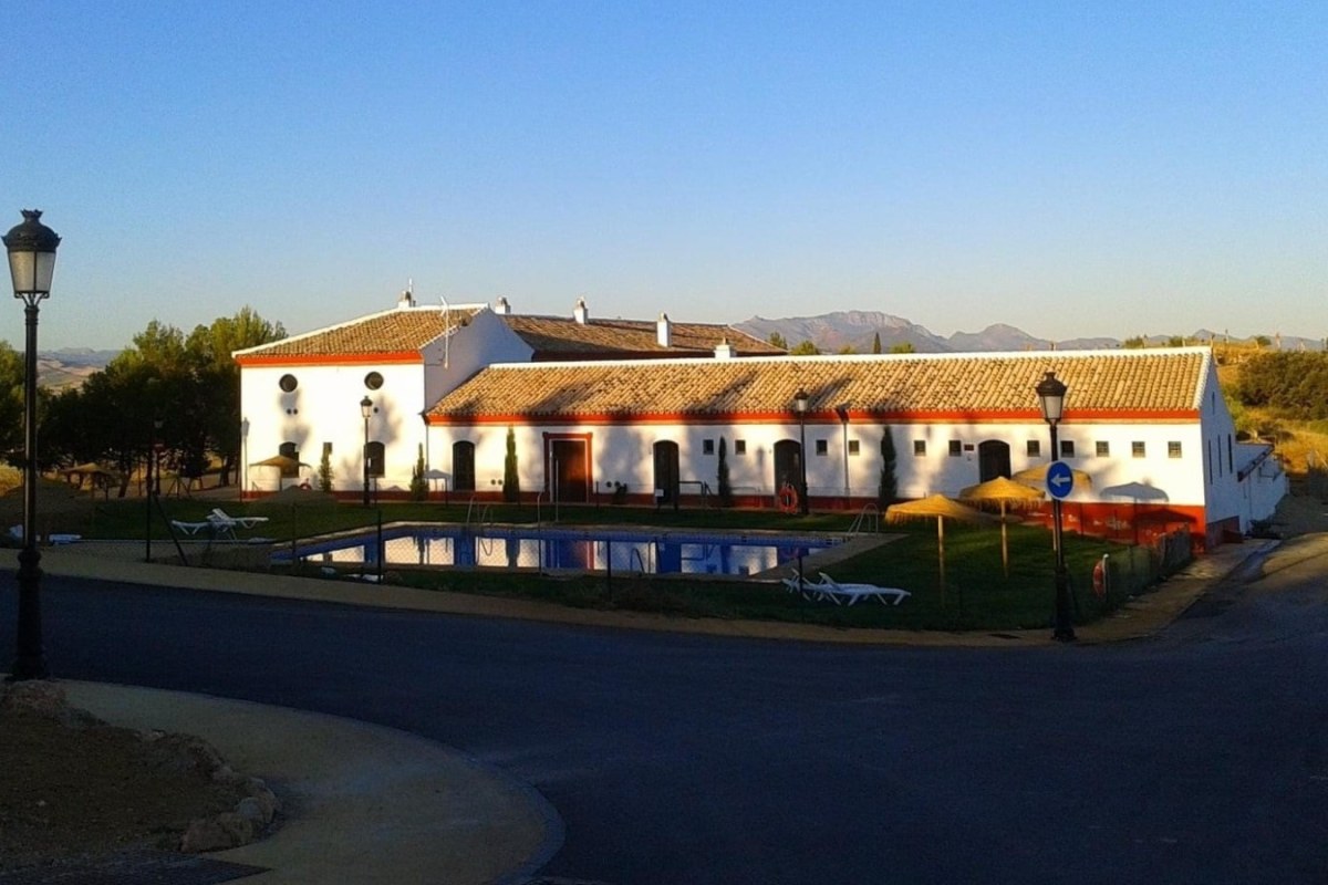 Cortijo de color blanco con una piscina enfrente de la entrada