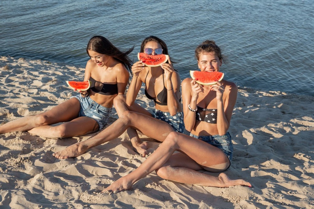 tres chicas comiendo sandía en la playa