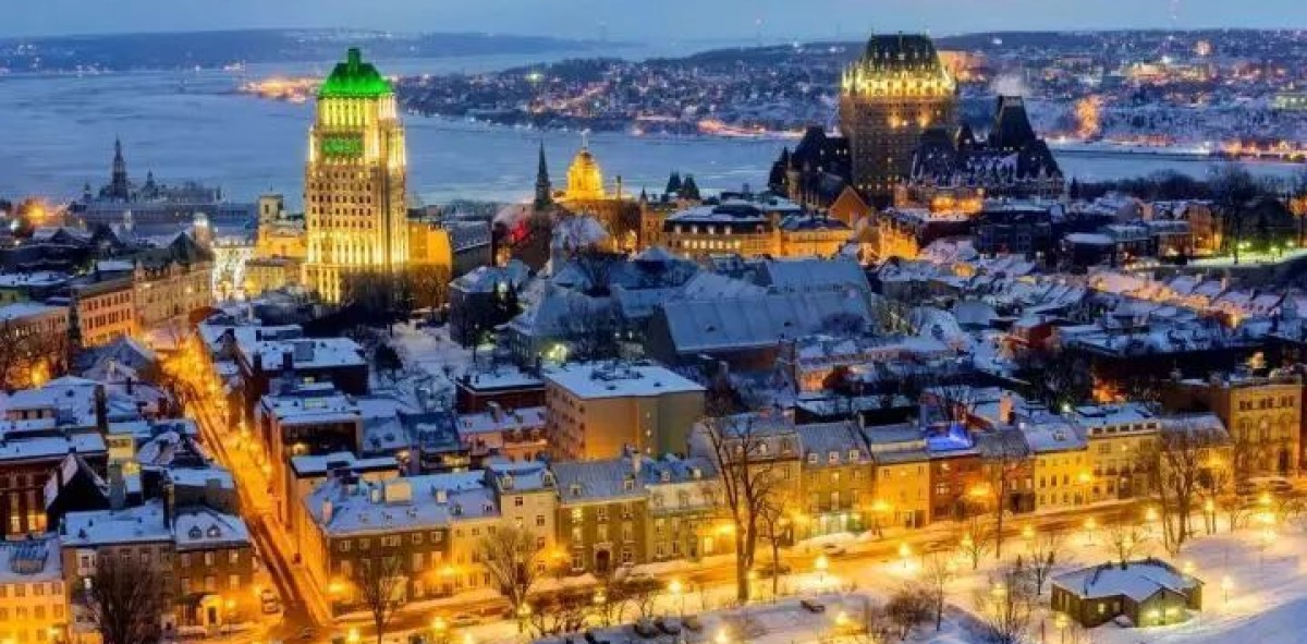 Panorámica de Quebec de noche y nevada, con los edificios iluminados, al fondo el rio donde esta situada