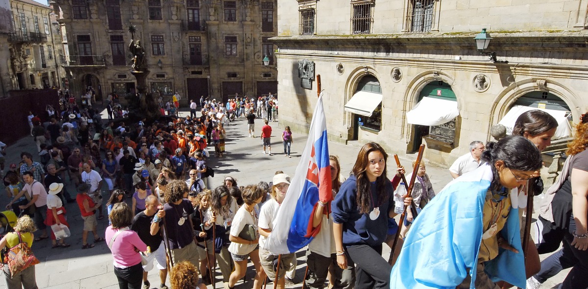 Peregrinos subiendo por una escalera con banderas