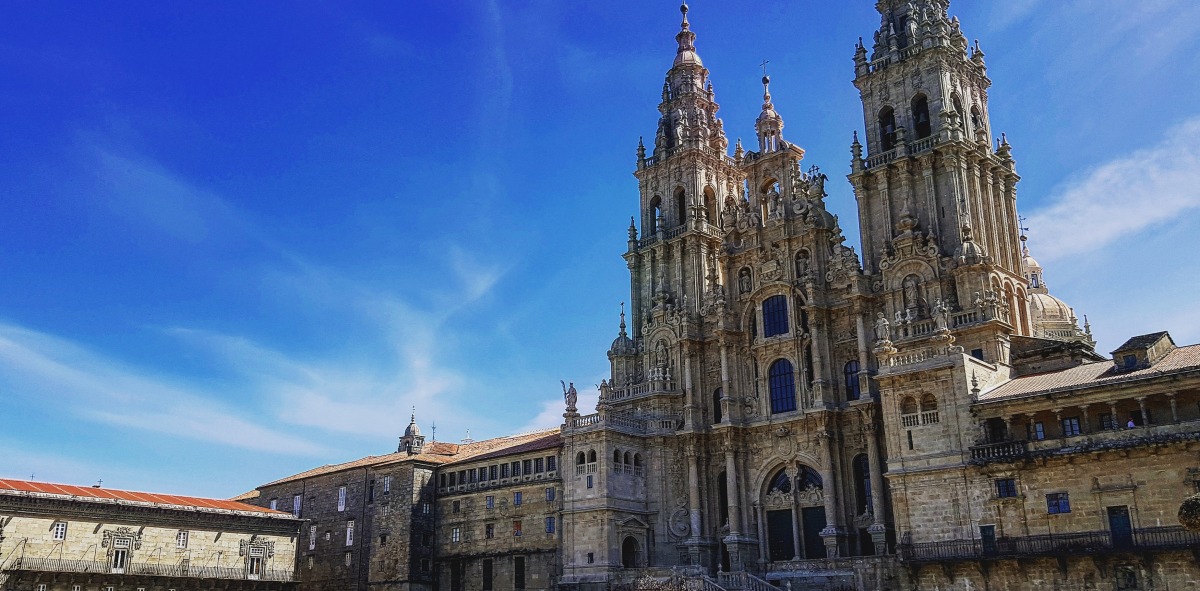 Plaza del Obradoiro con grupo de peregrinos sentados en el suelo, al fondo la catedral de Santiago